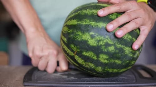 In the Kitchen a Person is Cutting Watermelon