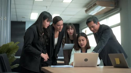 Group of business people looking at computer and discussing in modern office