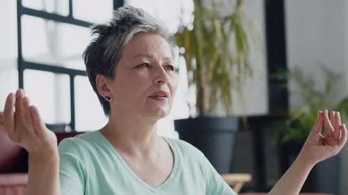 Mature Woman Meditating with Eyes Closed Indoors