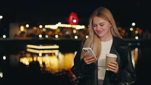 Young Lady Using Modern Smart Phone While Standing at Night City