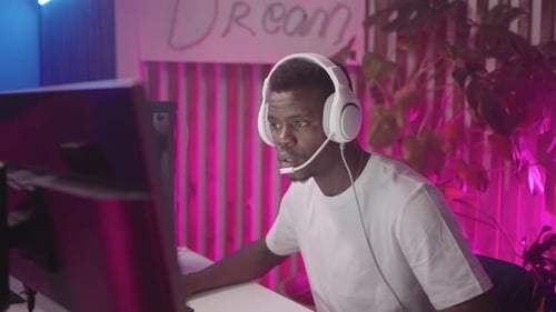 Young African Man Playing Computer Game In Computer Club Portrait Of Joyful Black Male With Headset