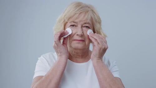 Senior Woman Cleansing Face with Cotton Pads