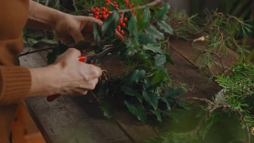 Hands Creating Christmas Wreath on Wooden Table