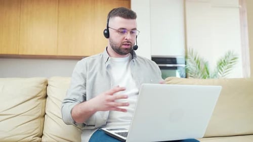 Man with Headset Video Calling on Laptop at Home