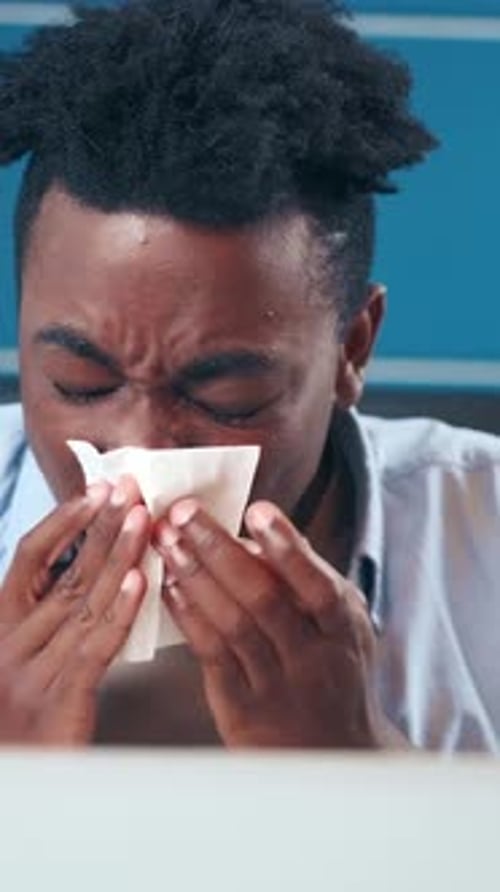 Man Struggles with Allergies During Springtime in a Bustling City Cafe