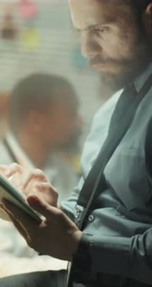Man in Suit Looks at Tablet in Office