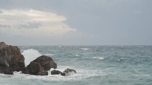 Strong Waves Crash into Sprays Against High Cliffs, with Spots of Blue Sky Visible, but the Storm.