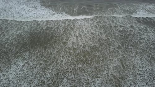Vue aérienne des vagues s'écrasant sur la plage vue à vol d'oiseau ci-dessus
