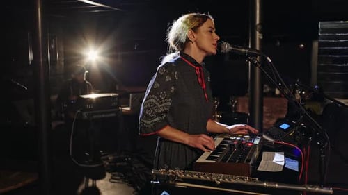 Woman Sings and Plays Keyboard on Stage
