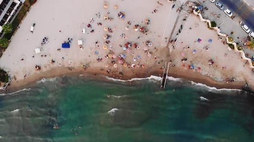 drone view of colorful parasols on the beach and wave in the sea