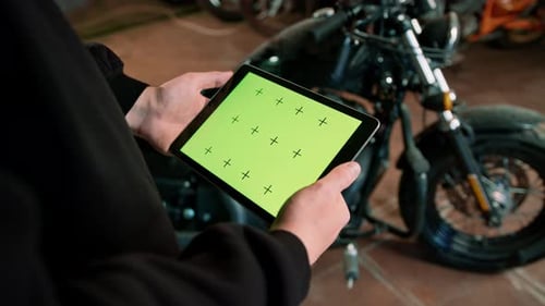 Creative authentic motorcycle workshop Biker mechanic in garage standing near motorcycle greenscreen