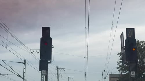 Visão do maquinista de um sinal vermelho ao entardecer, com linhas aéreas e vários sinais ferroviários