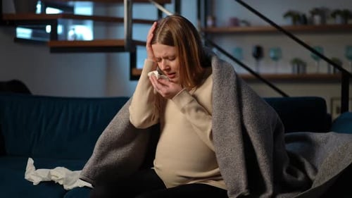 Blonde Woman with Cold Using Tissues on Sofa