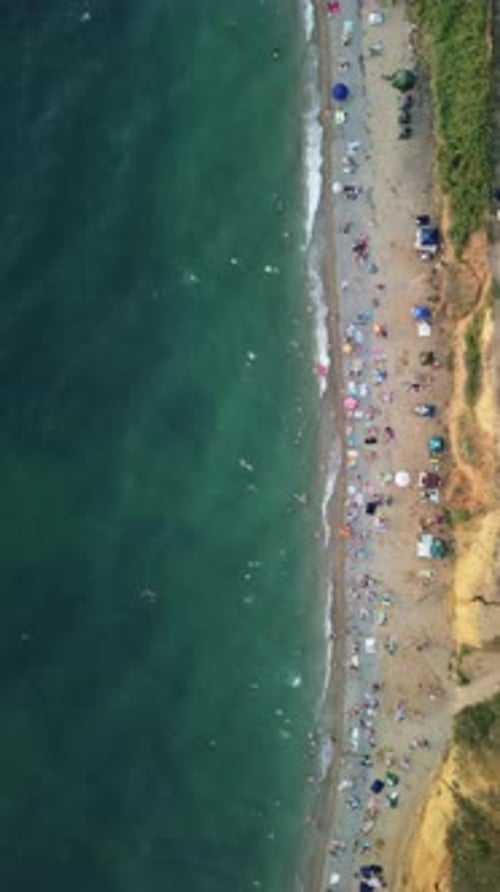 Luftaufnahme von schwimmenden Menschen am Sandstrand in Sea Bay mit transparentem blauem Wasser bei Sonnenuntergang in
