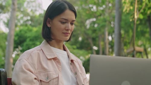 Young Woman Using Laptop Outdoors in Park