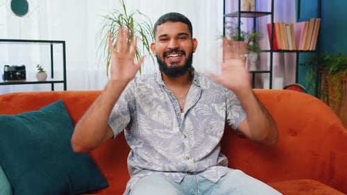 Young Adult Man Waving Hello from Couch