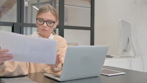 Woman Reviews Documents at Office Desk