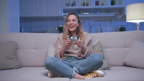 Smiling Woman Playing Video Game on Couch at Home