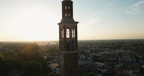 Glockenturm der katholischen St.-Nikolaus-Kirche mit Uhr gegen die strahlende Sonne bei Sonnenuntergang in Mira, Ve