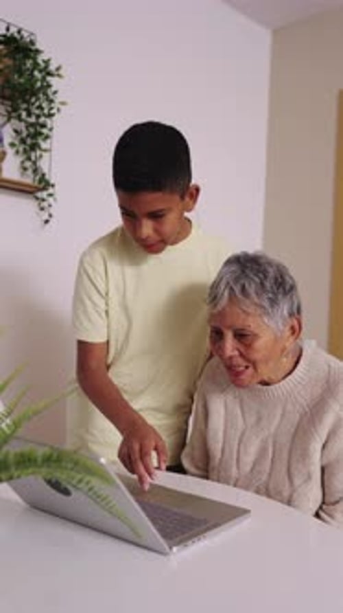 Child Helping Senior Woman Use Laptop at Home
