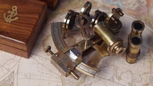 An antique nautical sextant and lenses with a rose wood box on a vintage world map