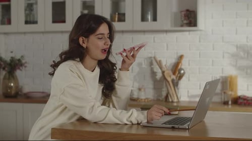 A Female Freelancer Working Remotely in a Home Office is Talking on the Phone with an Employer A