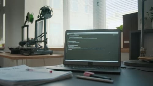 Laptop Displaying Code Alongside Two 3D Printers in Modern Classroom