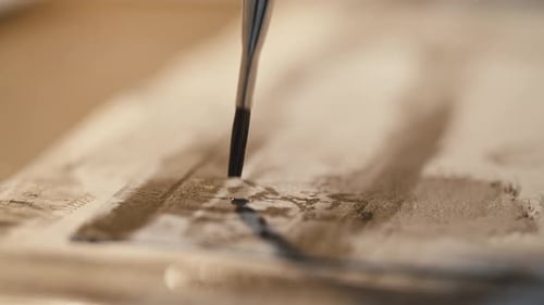 Nahaufnahme eines kleinen Pinsels, der kleine Farbpunkte auf weißem Papier macht