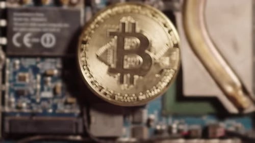 Slow zoom on bitcoin lying on the computer board.
