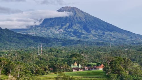 Aerial scenery of rural landscape with golden dome mosque and mountain on the background.