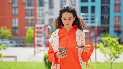 Happy Woman Using Smartphone and Credit Card For Online Shopping Outdoors