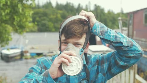 Man Putting On Respirator and Protective Face Shield