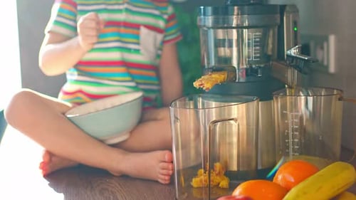 Petite fille préparant du jus de fruits frais sur la table dans la cuisine