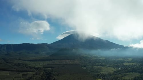 Aerial pan drone shot above trees revealing the forest and mountain horizon looking at a volcano and