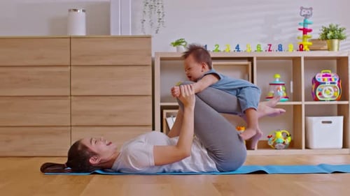Mother Lying on Yoga Mat Holding Baby