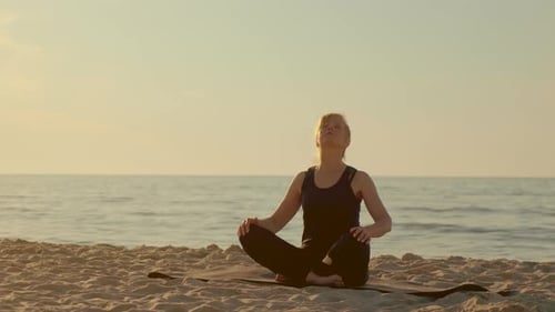 Woman Doing Yoga on a Sandy Beach at Sunset