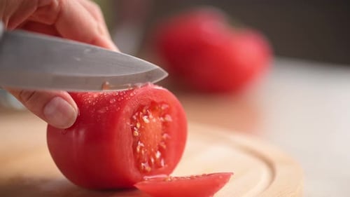 Slicing a Tomato with a Knife on Cutting Board