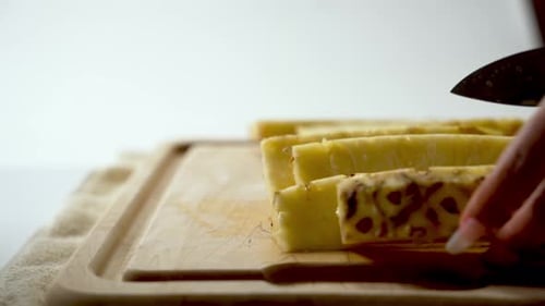 Person Slices Pineapple on Cutting Board