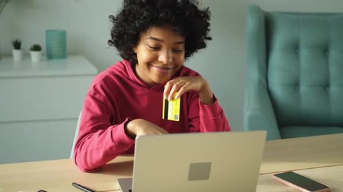 Young Adult Using Laptop with Credit Card at Desk