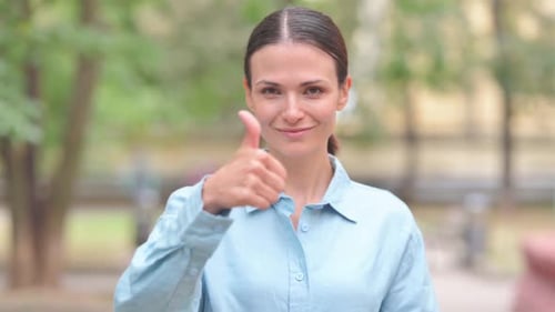 Confident Woman Giving Thumbs Up in Urban Setting