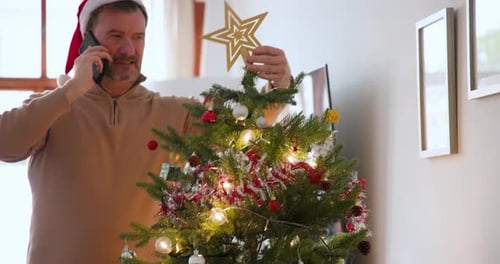 Man Decorating Christmas Tree While Talking on Phone