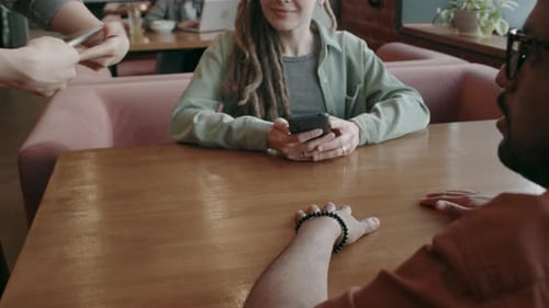 Waiter Giving Menu on Digital Tablet to Customer Sitting at Table in Cafe