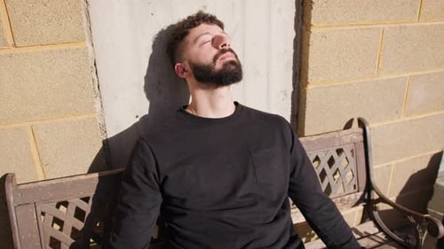 Man Resting on Bench in Urban Area