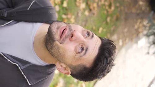 Vertikales Video eines Außenporträts eines jungen Mannes, der in den Himmel schaut.