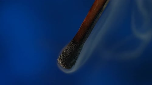 Burning Matchstick Macro Shot on a Blue Background