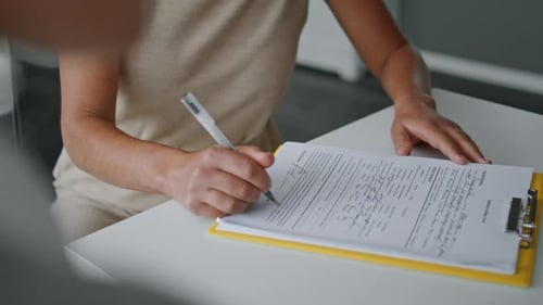 Woman Hands Signing Papers Sitting at Table Close Up