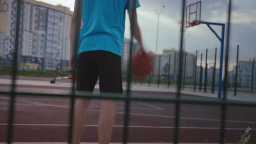 Teen Training to Play Basketball in Playground at Sunset Young Man Playing Basketball in Summer