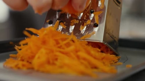 Fresh Carrot Being Grated on a Steel Grater