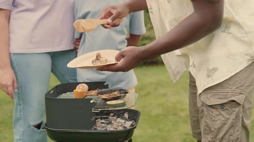 An African Dad Cooks Grill Vegetables for His Multiethnic Family