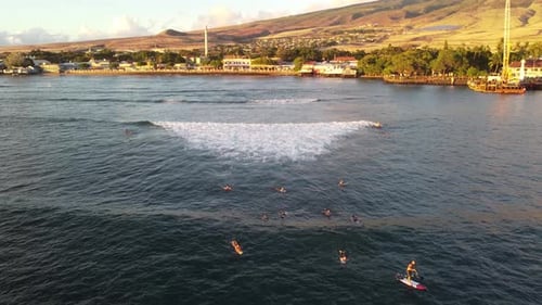 Surfers waiting and catching waves in Hawaii with a view of Maui in the back